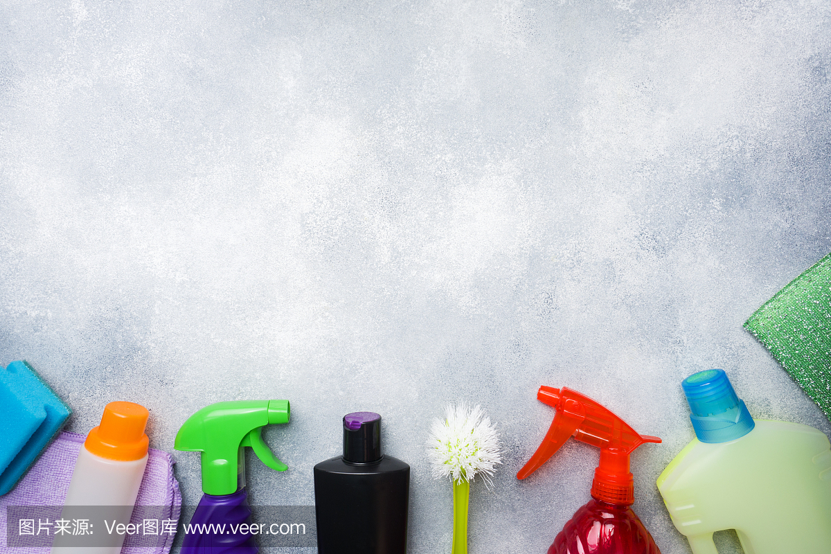瓶子與洗滌劑,刷子和海綿在混凝土背景。色彩鮮艷的清潔產品。家庭清潔的概念。俯視圖,復制空間。